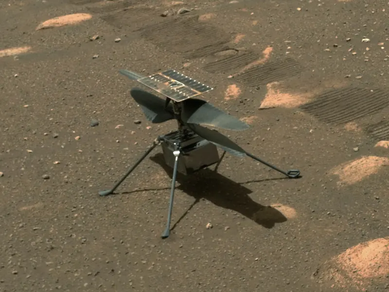 A small helicopter with two long rotor blades standing on the Martian ground