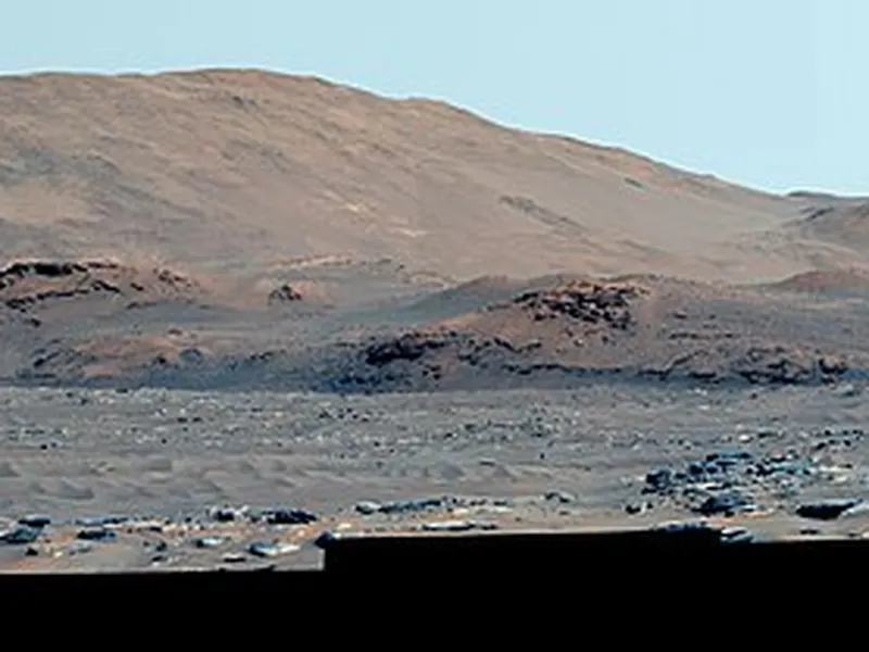 A wide view of rocky ground and low hills inside Jezero Crater on Mars