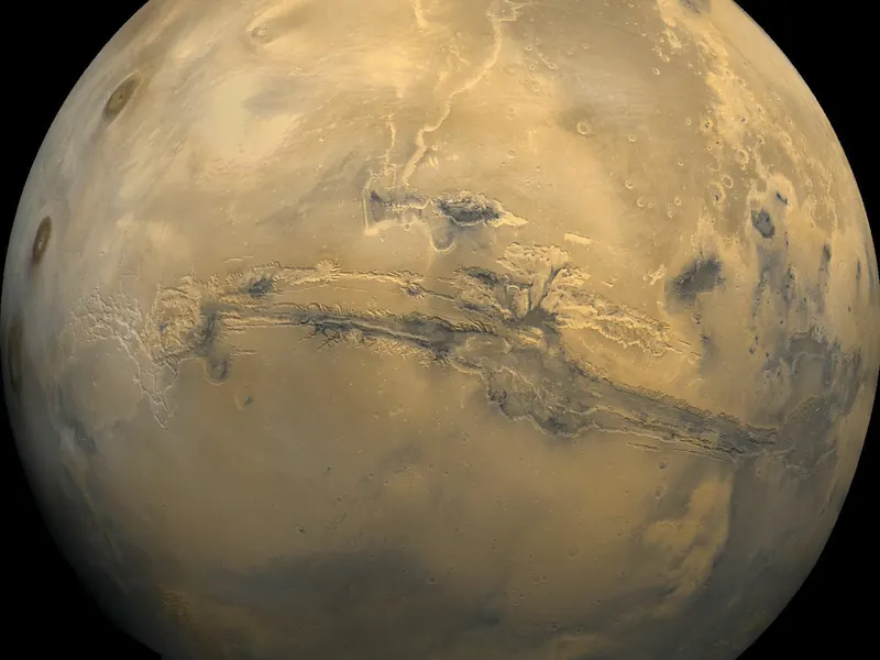 A wide view of Mars with a huge canyon system stretching across the middle of the planet